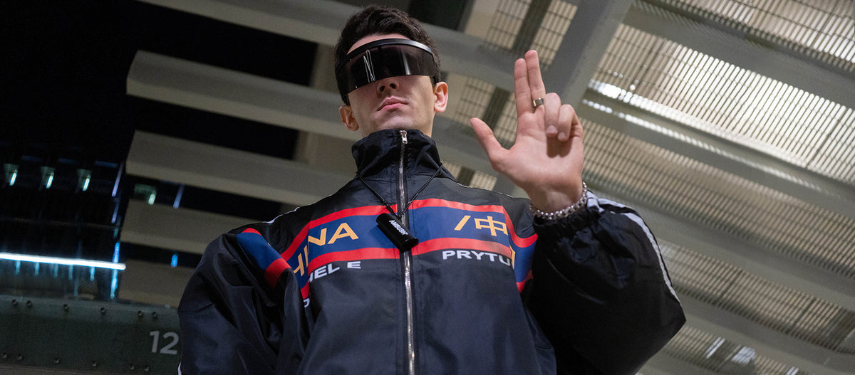 Model wearing a futuristic jacket and visor in an industrial setting