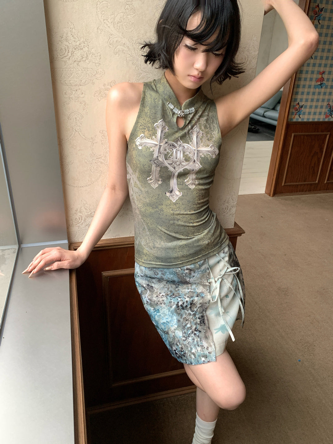 4RE1GN TRIPLE CROSS mandarin sleeveless top in olive green — front modeled view with the BLUE BLOOM layered skirt