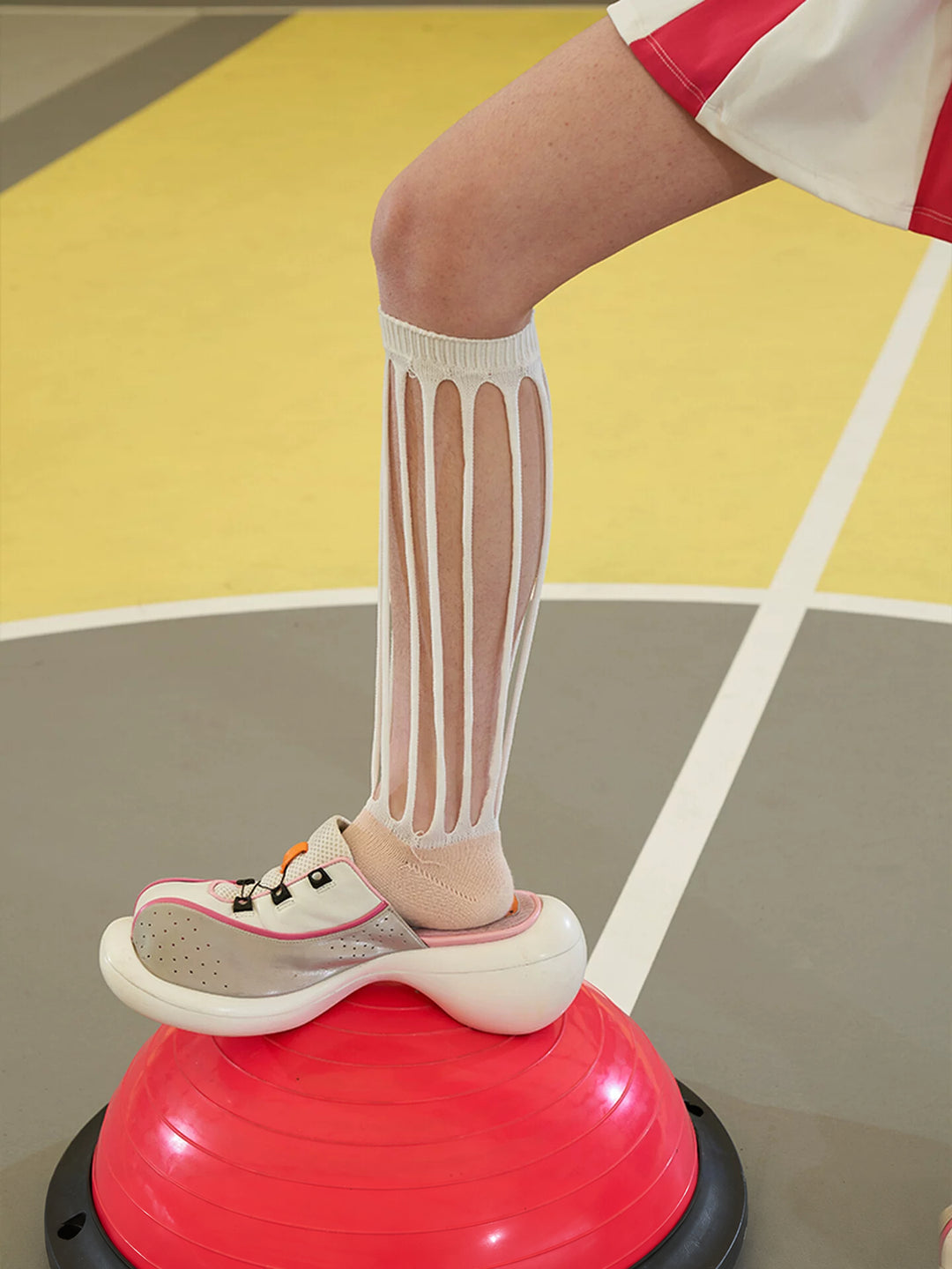 NEXT PASSPORT MULTIPASS cutout knee-high socks — white cutout sock with ribbed cuff, worn on a red exercise platform.