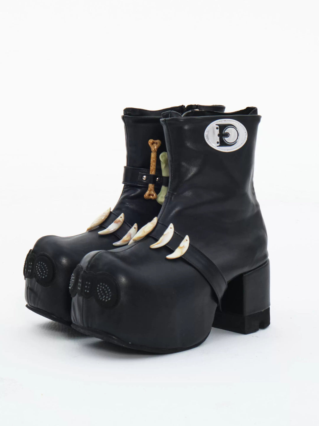EMBRYO BONE LIFT detachable-bone platform boots — three-quarter front view of the black pair with sculptural toes and bone ornaments