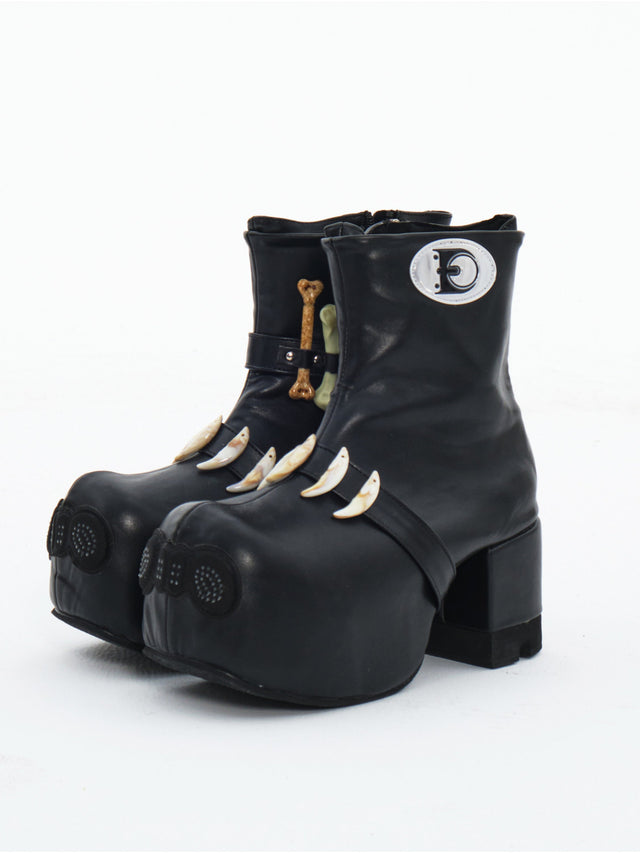 EMBRYO BONE LIFT detachable-bone platform boots — three-quarter front view of the black pair with sculptural toes and bone ornaments