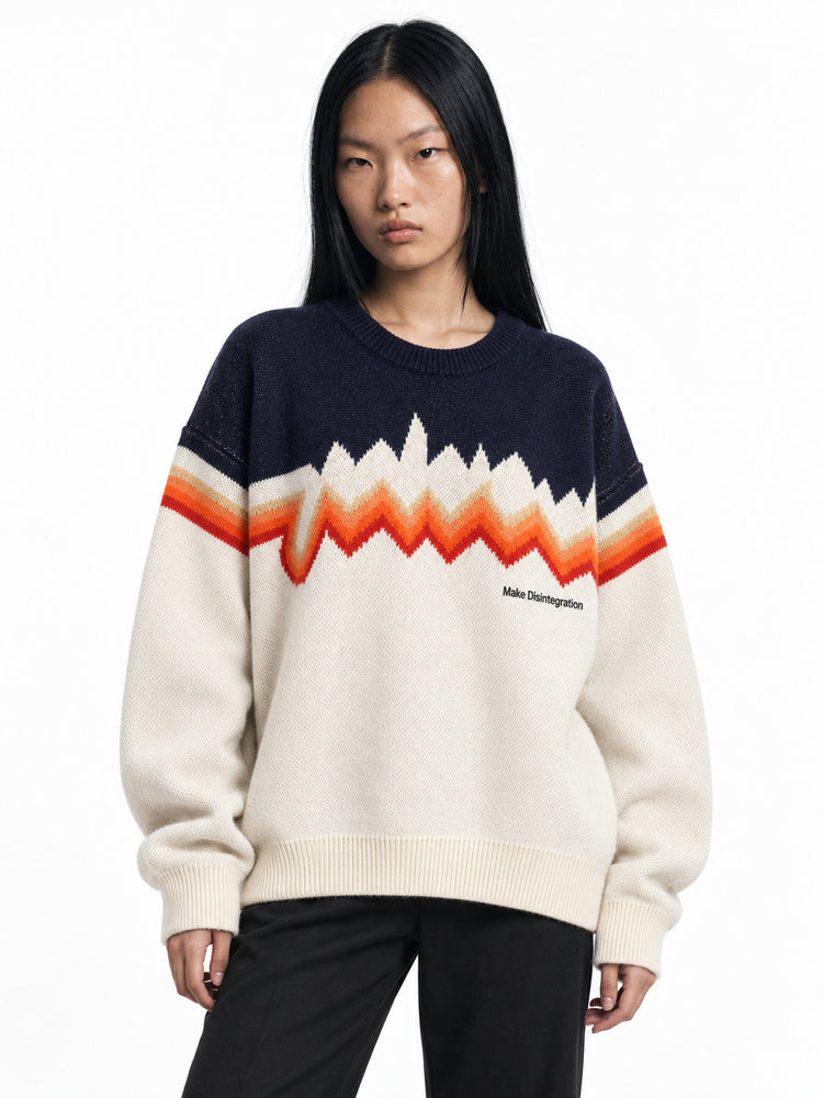 Model wearing the cream and navy Make Disintegration sweater with orange zigzag chest bands, front view.