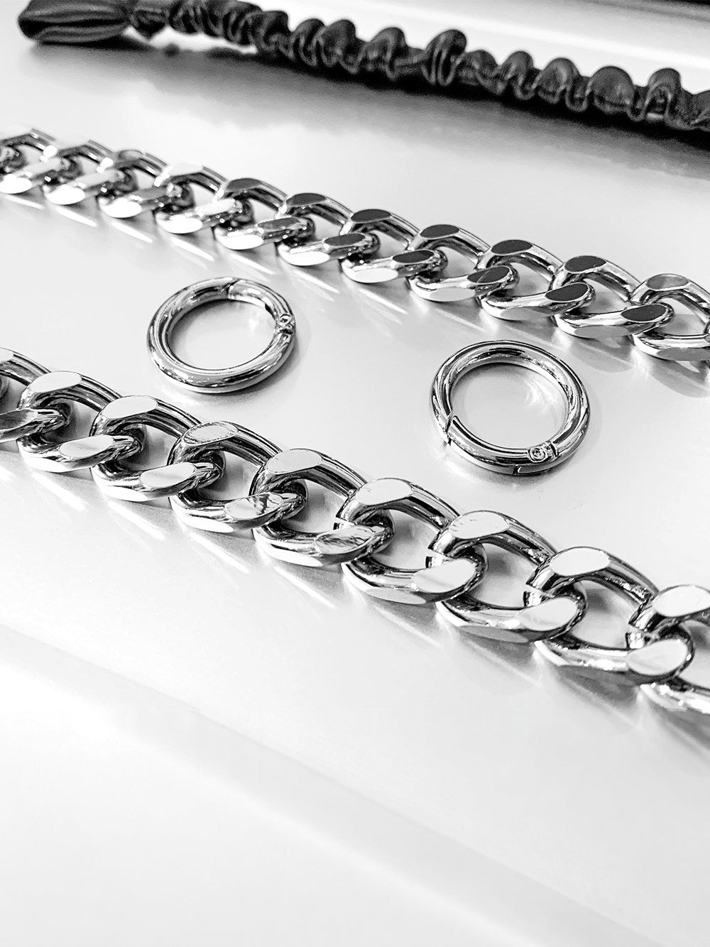 WRAVEN gathered faux-leather curb-chain belt — close-up of silver-tone curb links and round spring-gate connectors