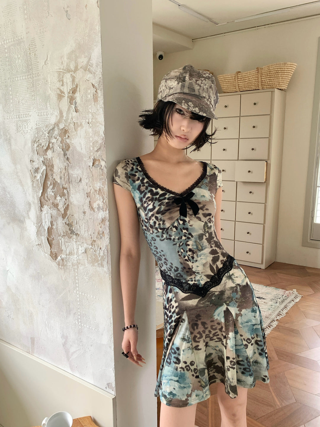 4RE1GN SEA BLUE leopard floral lace dress in gray blue — close front modeled view beside a doorway
