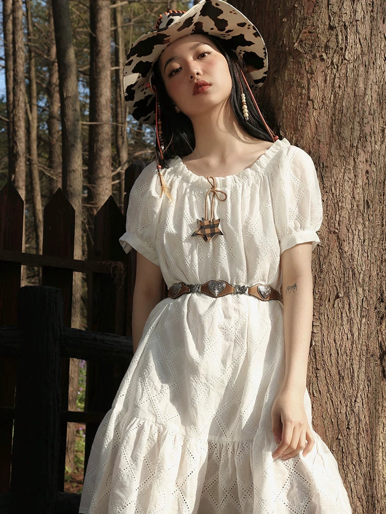 NEXT PASSPORT heart-cutout western PU belt in brown and silver — modeled with a white dress in a front view.