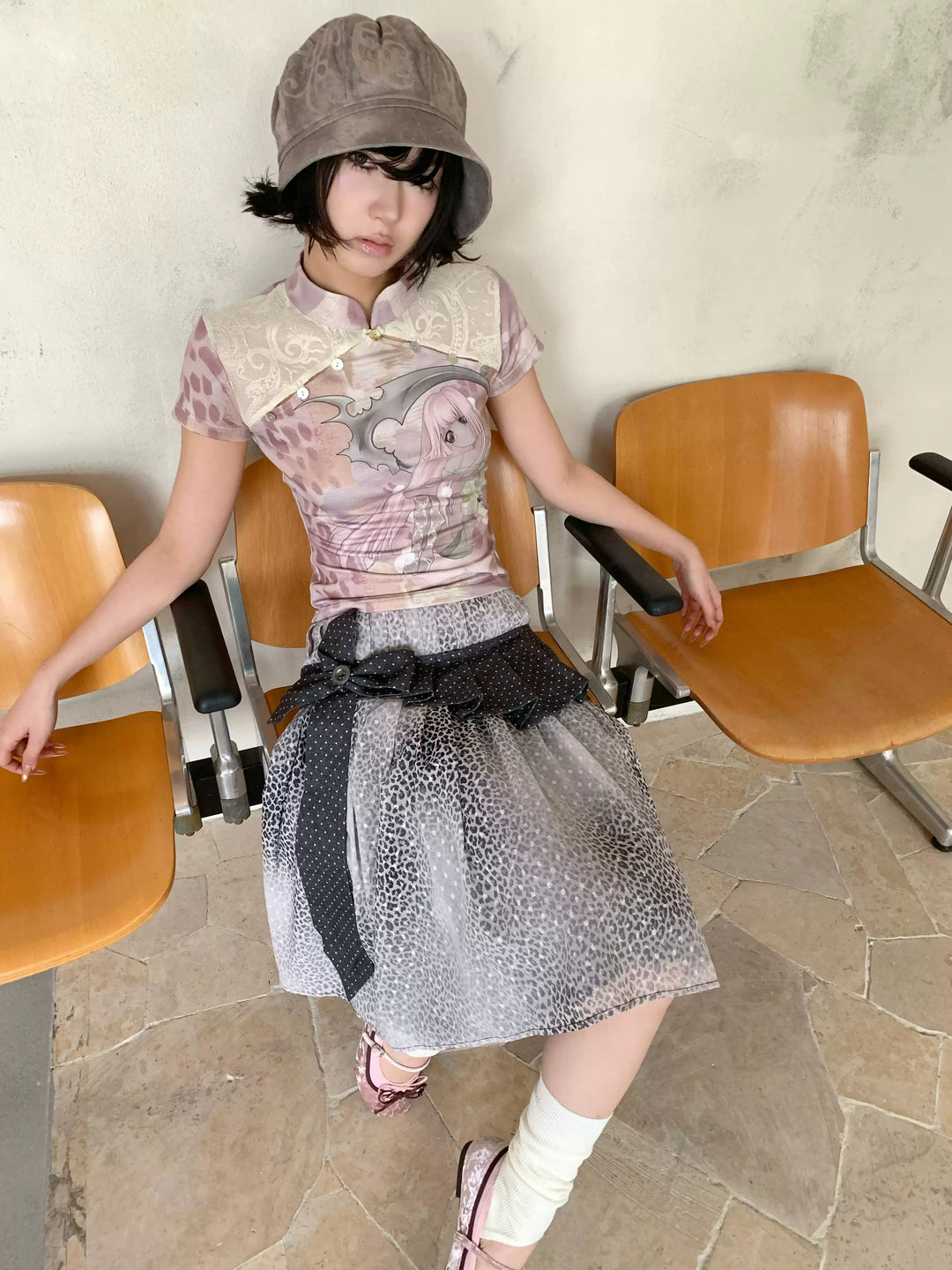 4RE1GN PINK REAPER lace-panel mandarin tee in pink multicolor — full-length modeled view between chairs with a gray leopard-print skirt
