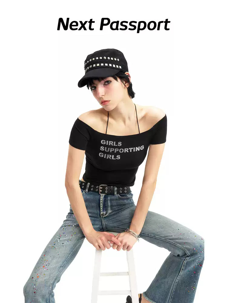 NEXT PASSPORT GIRLS SUPPORTING GIRLS rhinestone off-shoulder crop tee — black seated modeled front view.