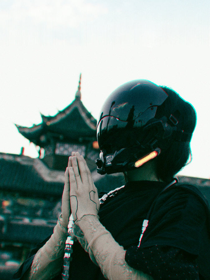 FOCKSHOP VOID illuminated tactical mask — side modeled view with hands together beside a pagoda