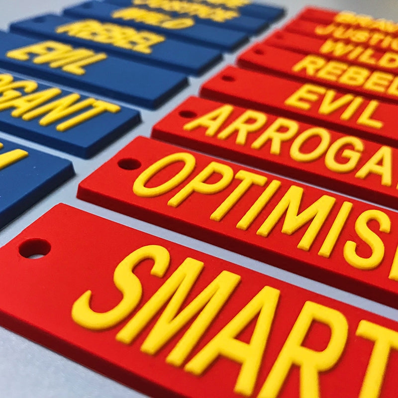 EOH-STUDIO BTBM raised yellow lettering on red and blue silicone earring panels, macro detail.