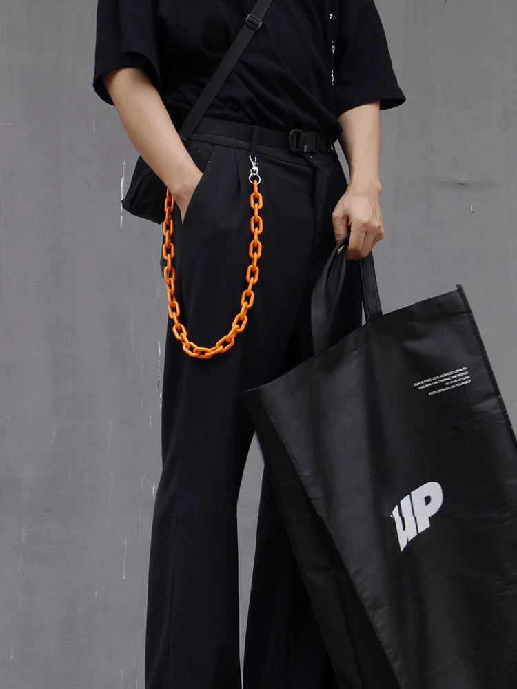 COLLATERAL — orange resin trouser chain styled with black trousers