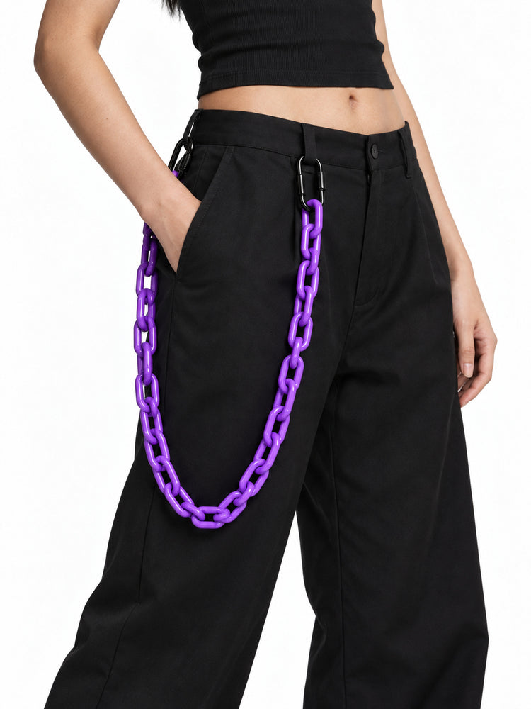 COLLATERAL purple resin trouser chain close-up, styled with black trousers on Chell — AI-generated styling image