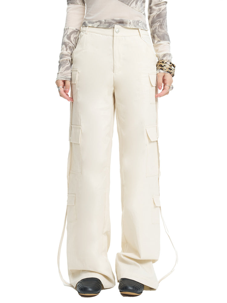 NEXT PASSPORT white drawstring multi-pocket cargo pants in white — front close studio view showing the multi-pocket legs.