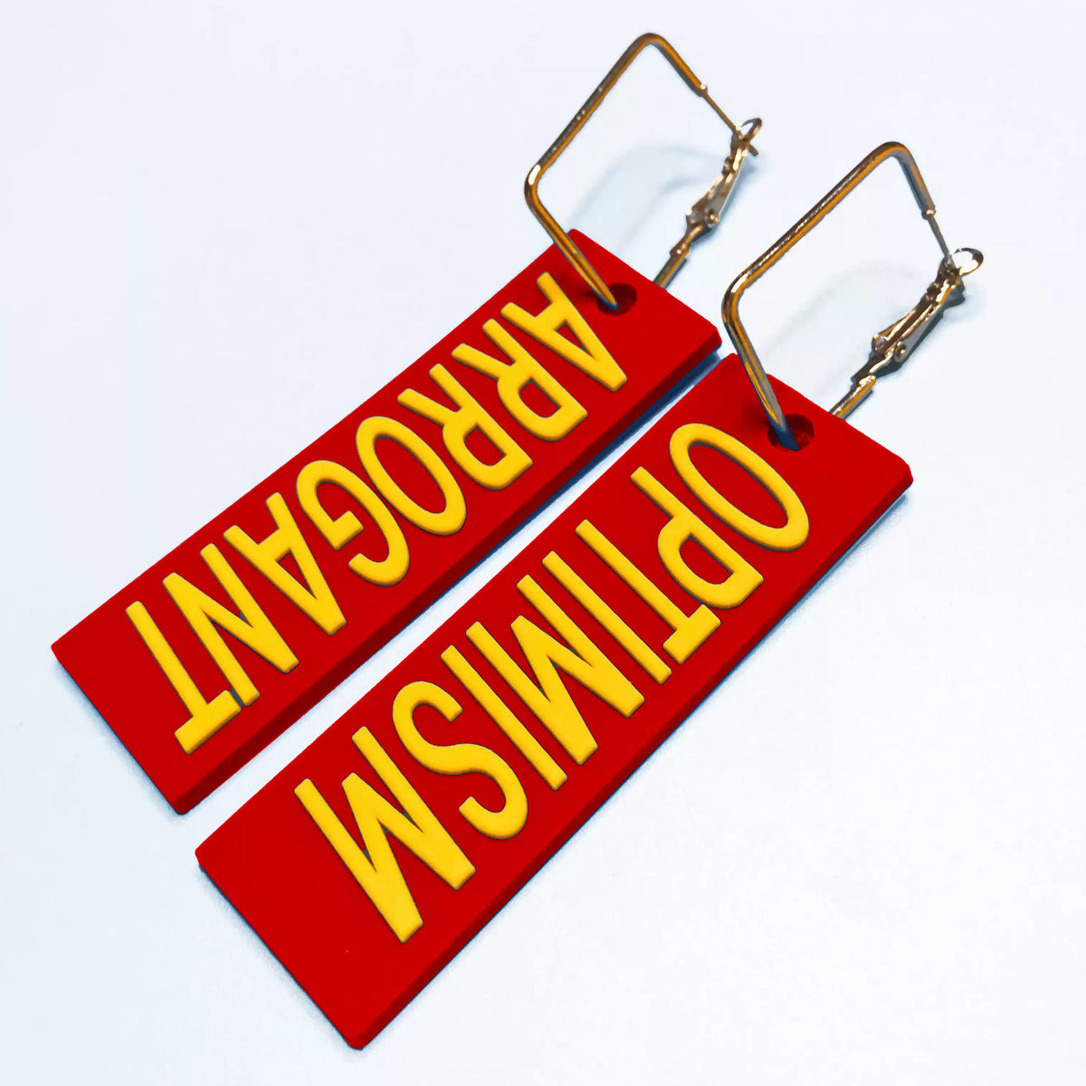 EOH-STUDIO BTBM red ARROGANT and OPTIMISM earrings with rectangular metal hoops on a pale background; source options sold singly.