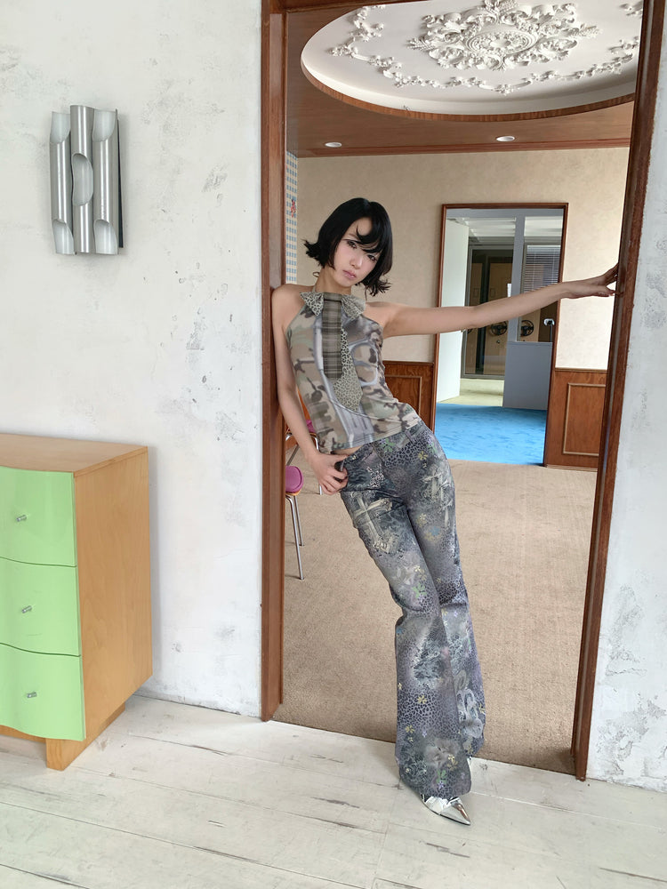 4RE1GN DEAR NINA camouflage tie-neck halter top in camo green — full-length modeled view in a doorway with one arm extended