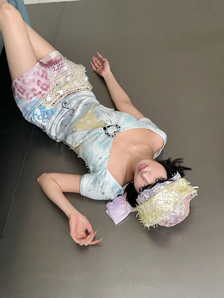 4RE1GN BLUE BLOOM patchwork short-sleeve tee in blue multicolor — modeled view reclining on the floor with a pastel mini skirt