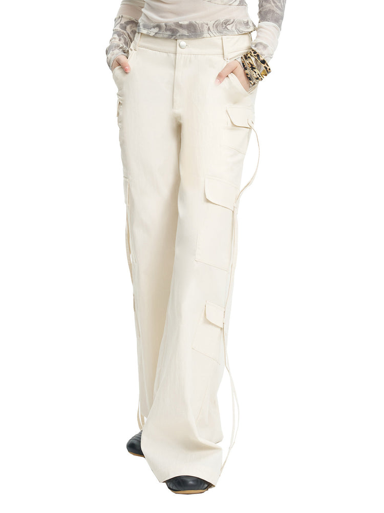 NEXT PASSPORT white drawstring multi-pocket cargo pants in white — three-quarter close studio view showing pocket placement.