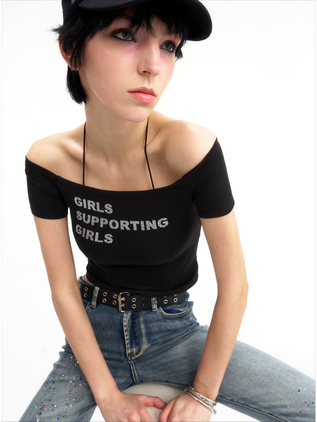 NEXT PASSPORT GIRLS SUPPORTING GIRLS rhinestone off-shoulder crop tee — black close modeled front view.