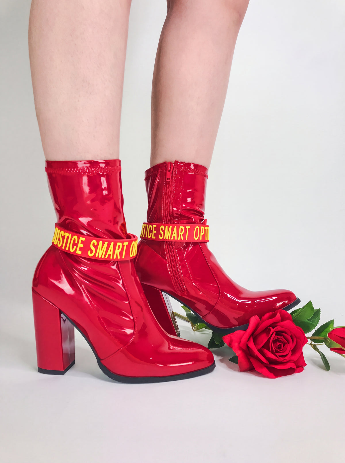 EOH-STUDIO BTBM red raised-letter silicone choker styled around red boots on a clean white studio background.
