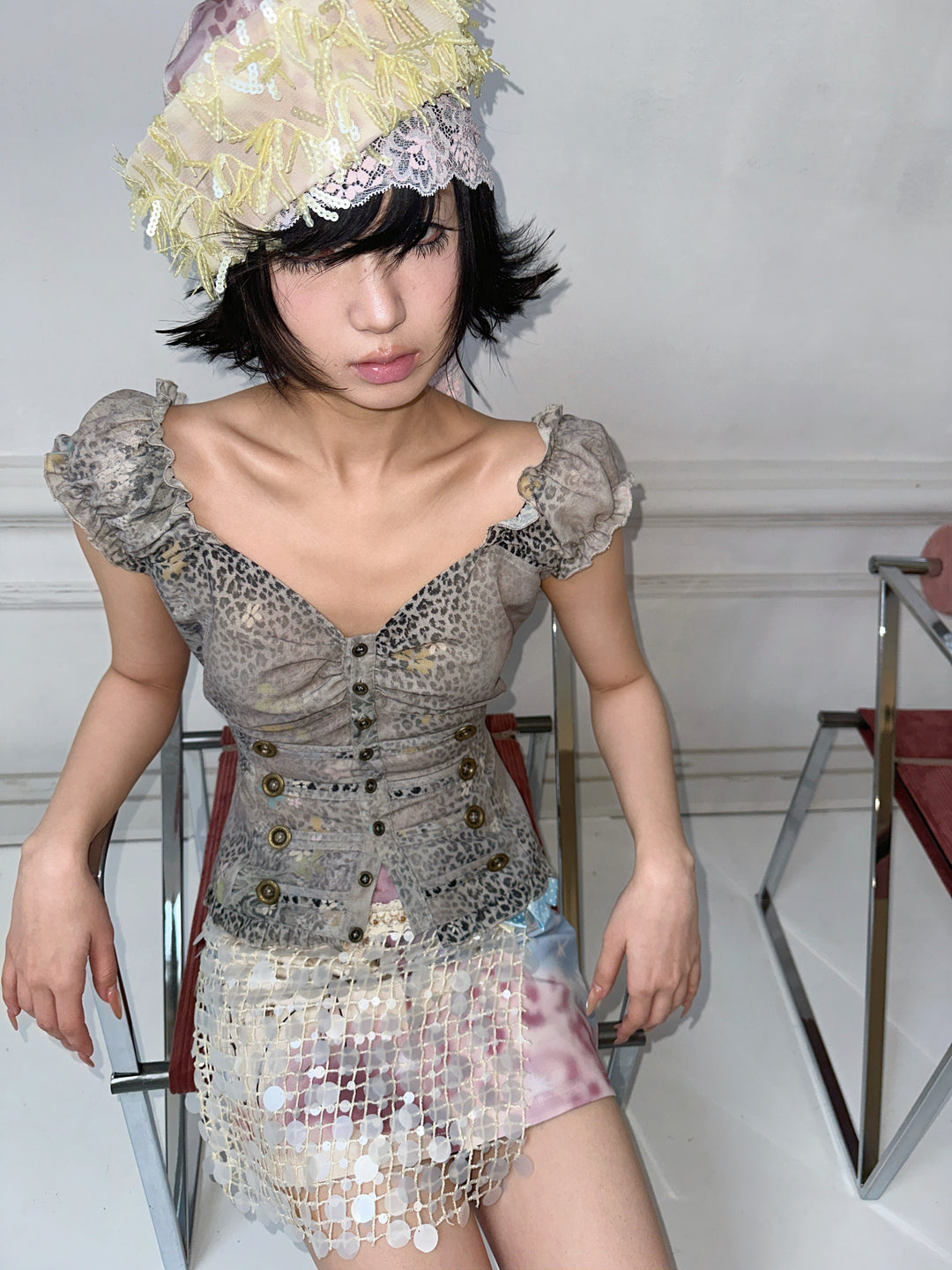 4RE1GN DREAM GARDEN sequin-panel mini skirt in pink multicolor — seated modeled view styled with a gray leopard-print top