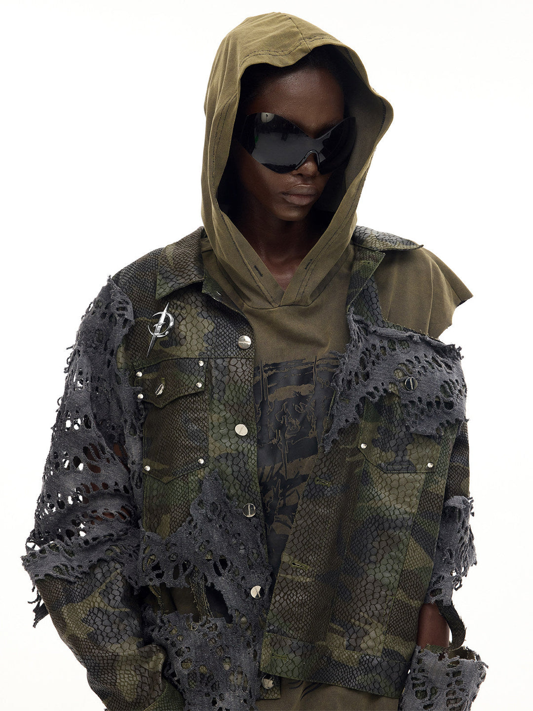 PINKSPINK ELECTRIC MOON distressed camouflage denim jacket — front close modeled view layered over an olive hood with sunglasses