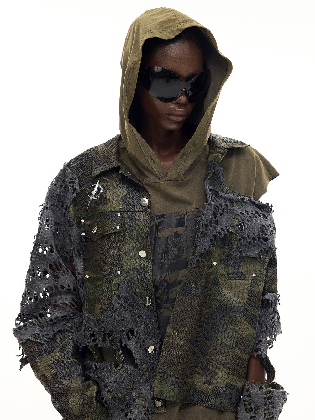 PINKSPINK ELECTRIC MOON distressed camouflage denim jacket — front close modeled view layered over an olive hood with sunglasses