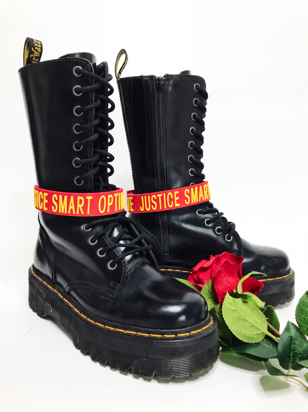 EOH-STUDIO BTBM red raised-letter silicone choker styled around black boots on a clean white studio background.