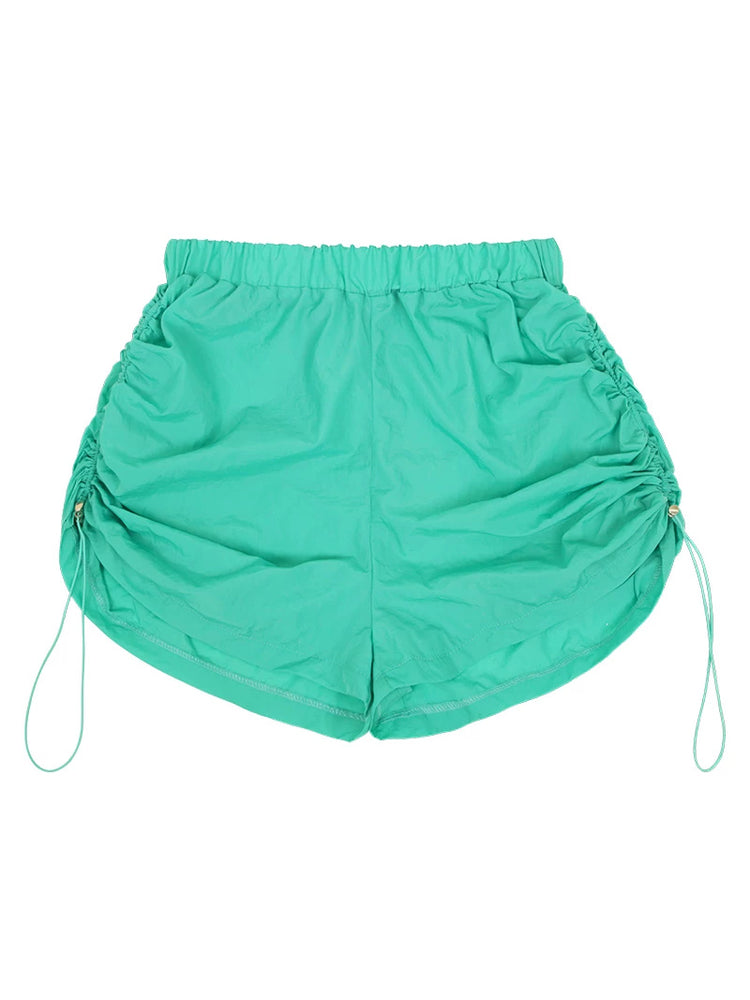NEXT PASSPORT side-ruched drawstring mini shorts in green, flat lay