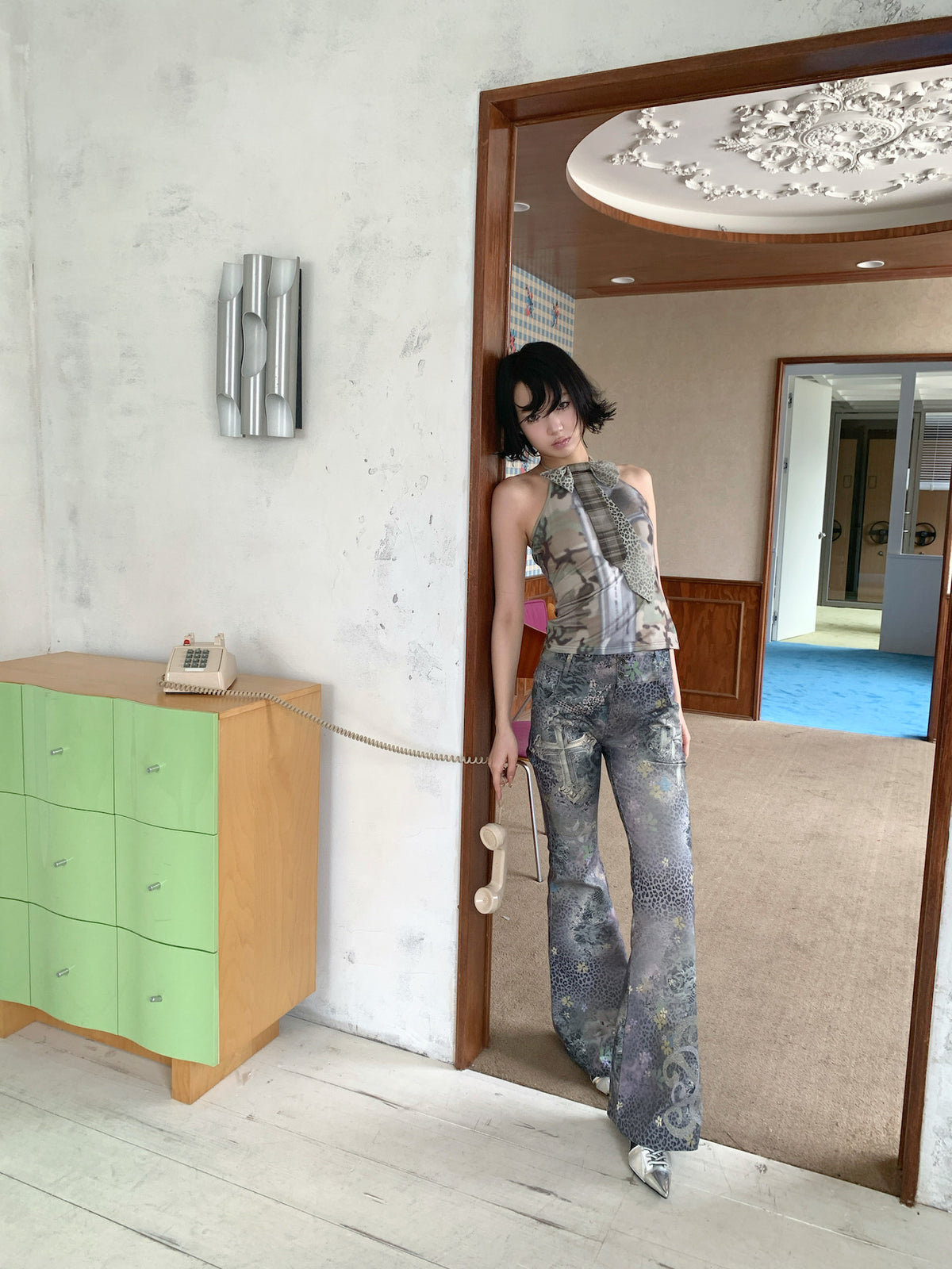 4RE1GN DEAR NINA camouflage tie-neck halter top in camo green — front modeled view holding a telephone at the side