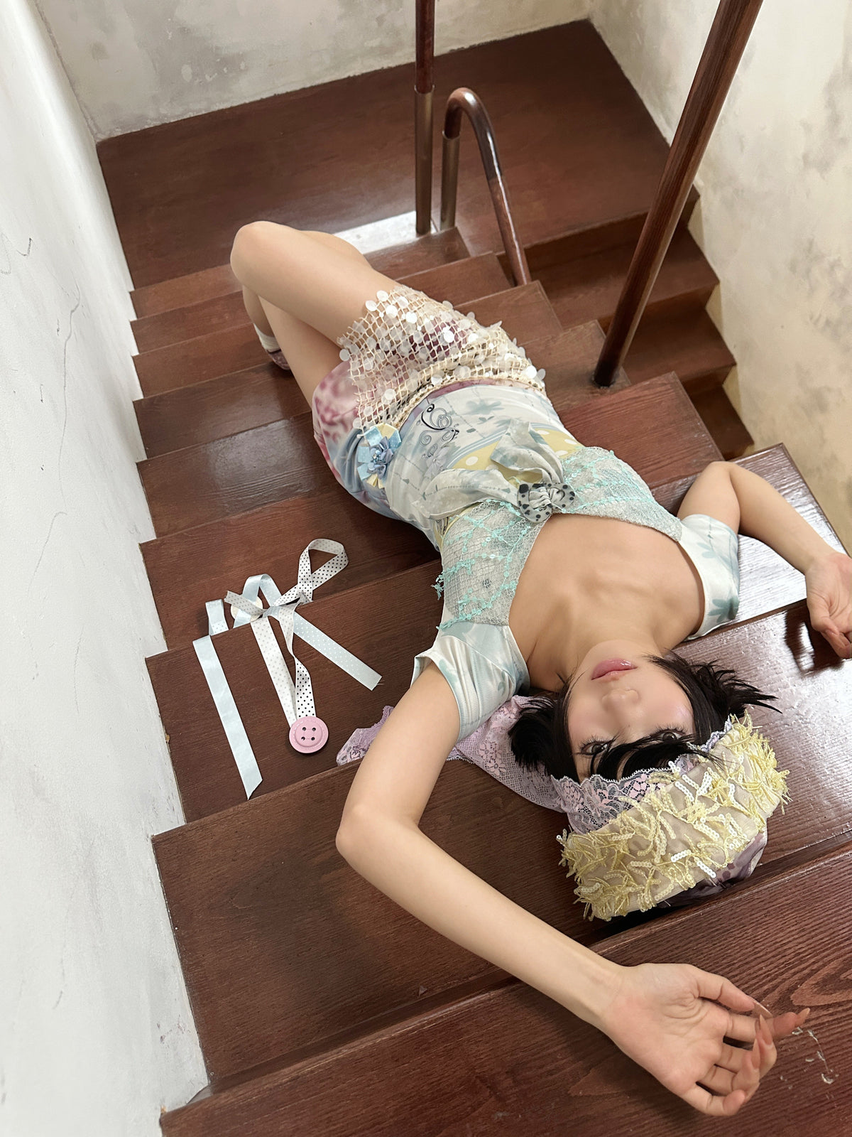 4RE1GN BLUE BLOOM patchwork short-sleeve tee in blue multicolor — modeled view reclining on stairs with a pastel mini skirt