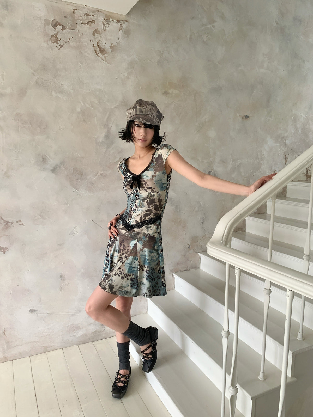 4RE1GN SEA BLUE leopard floral lace dress in gray blue — three-quarter modeled view holding the stair rail