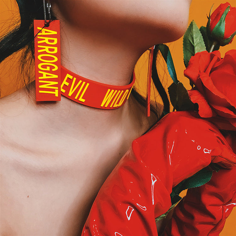 EOH-STUDIO BTBM red ARROGANT earring, side view of the long silicone panel and raised yellow letters.