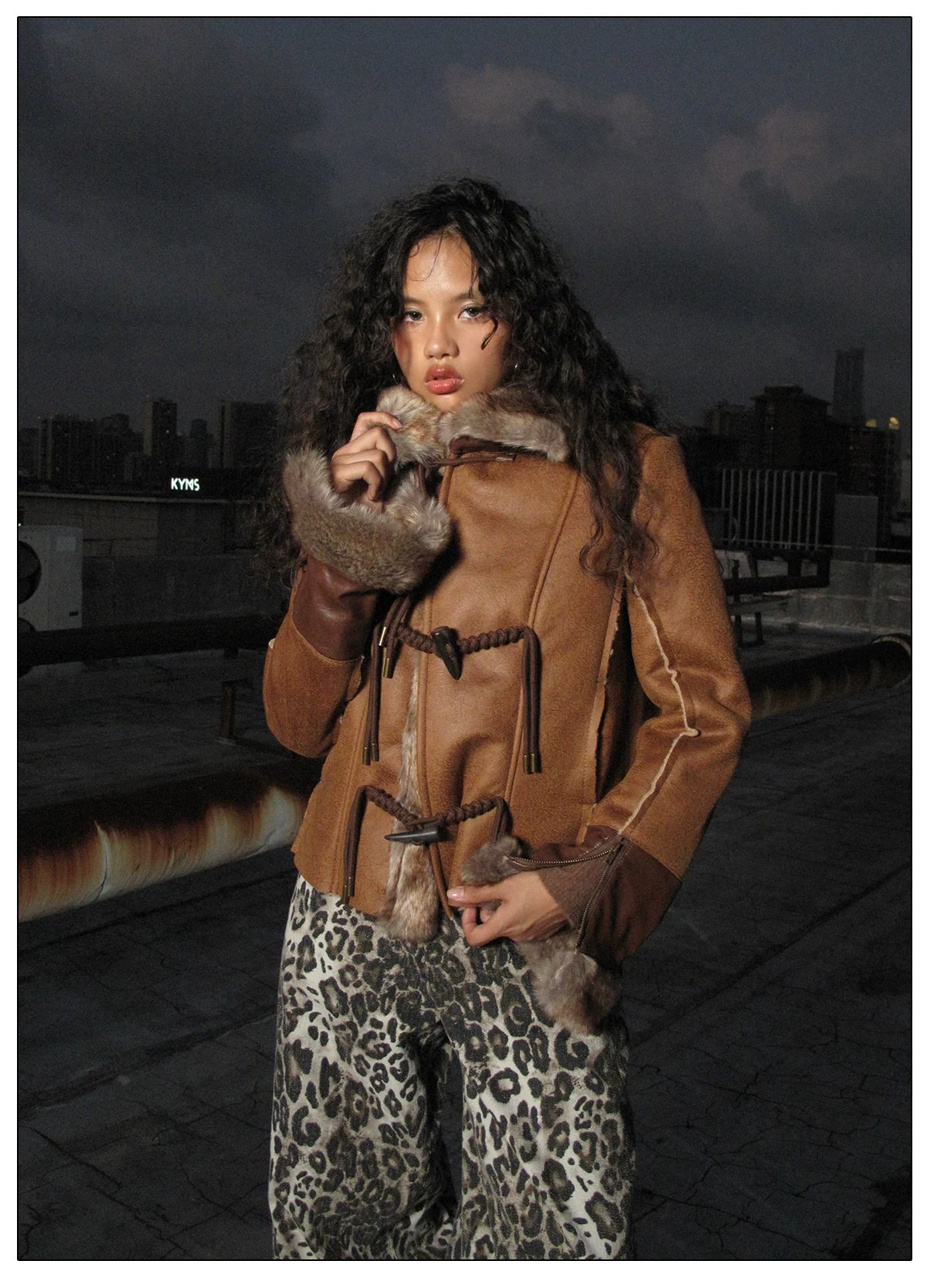 NEXT PASSPORT dark-brown rope-toggle shearling cropped jacket, nighttime rooftop close-up touching collar