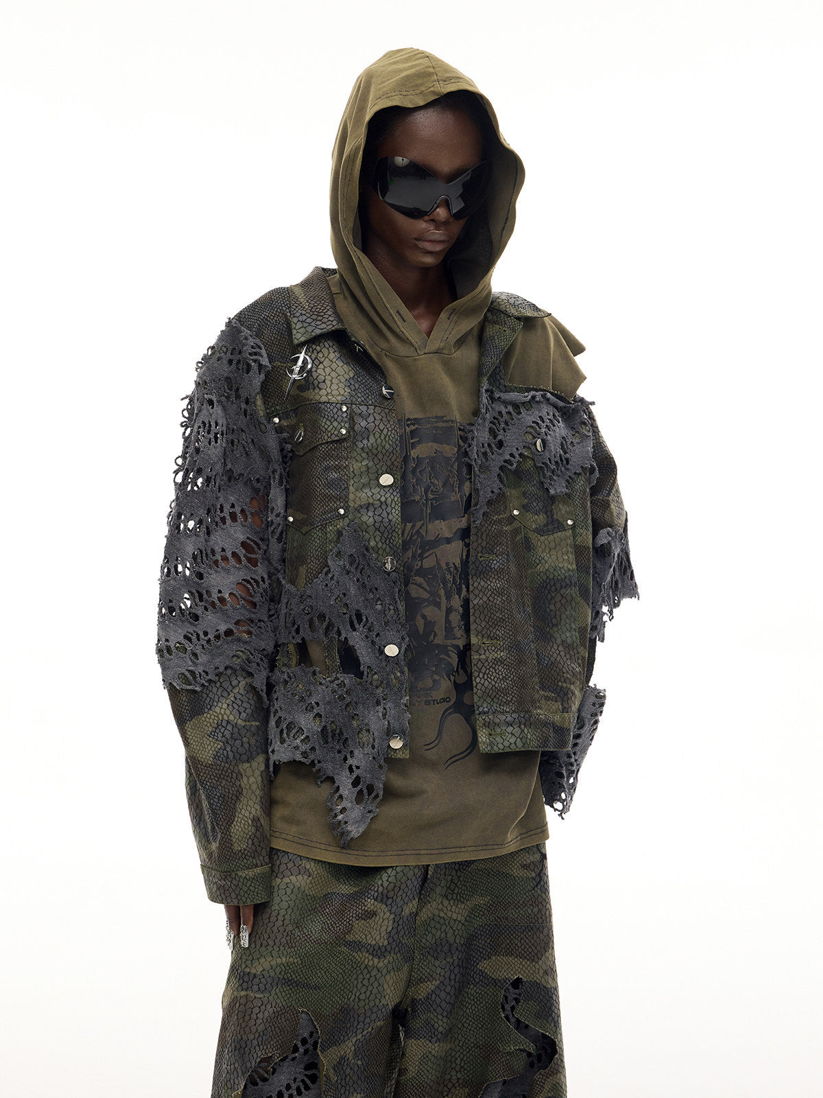 PINKSPINK ELECTRIC MOON distressed camouflage denim jacket — front modeled view with the olive hood raised and hands in pockets
