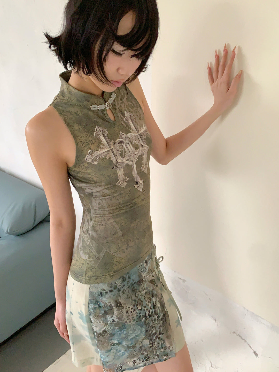 4RE1GN TRIPLE CROSS mandarin sleeveless top in olive green — high-angle modeled view showing the collar clasp and front print