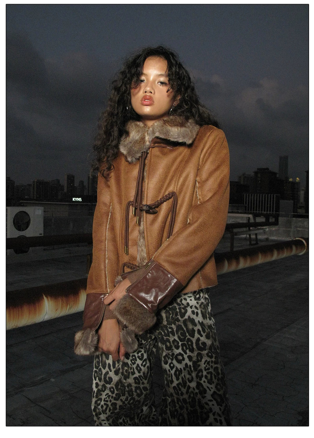 NEXT PASSPORT dark-brown rope-toggle shearling cropped jacket, nighttime rooftop three-quarter pose