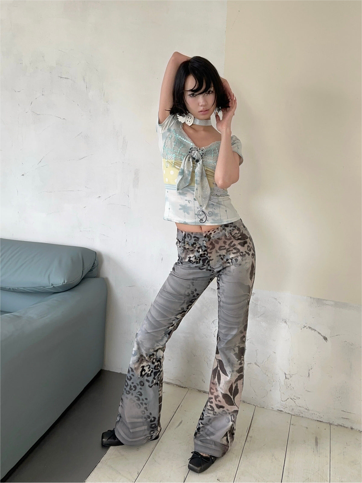 4RE1GN BLUE BLOOM patchwork short-sleeve tee in blue multicolor — modeled view with arms raised and gray leopard-print trousers