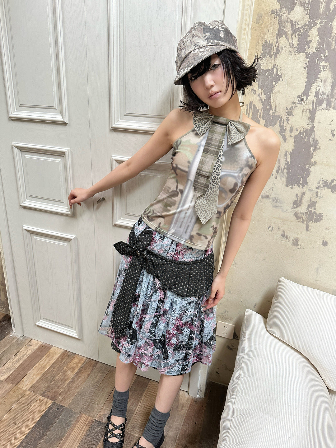 4RE1GN DEAR NINA camouflage tie-neck halter top in camo green — full-length modeled view beside a door with a layered skirt