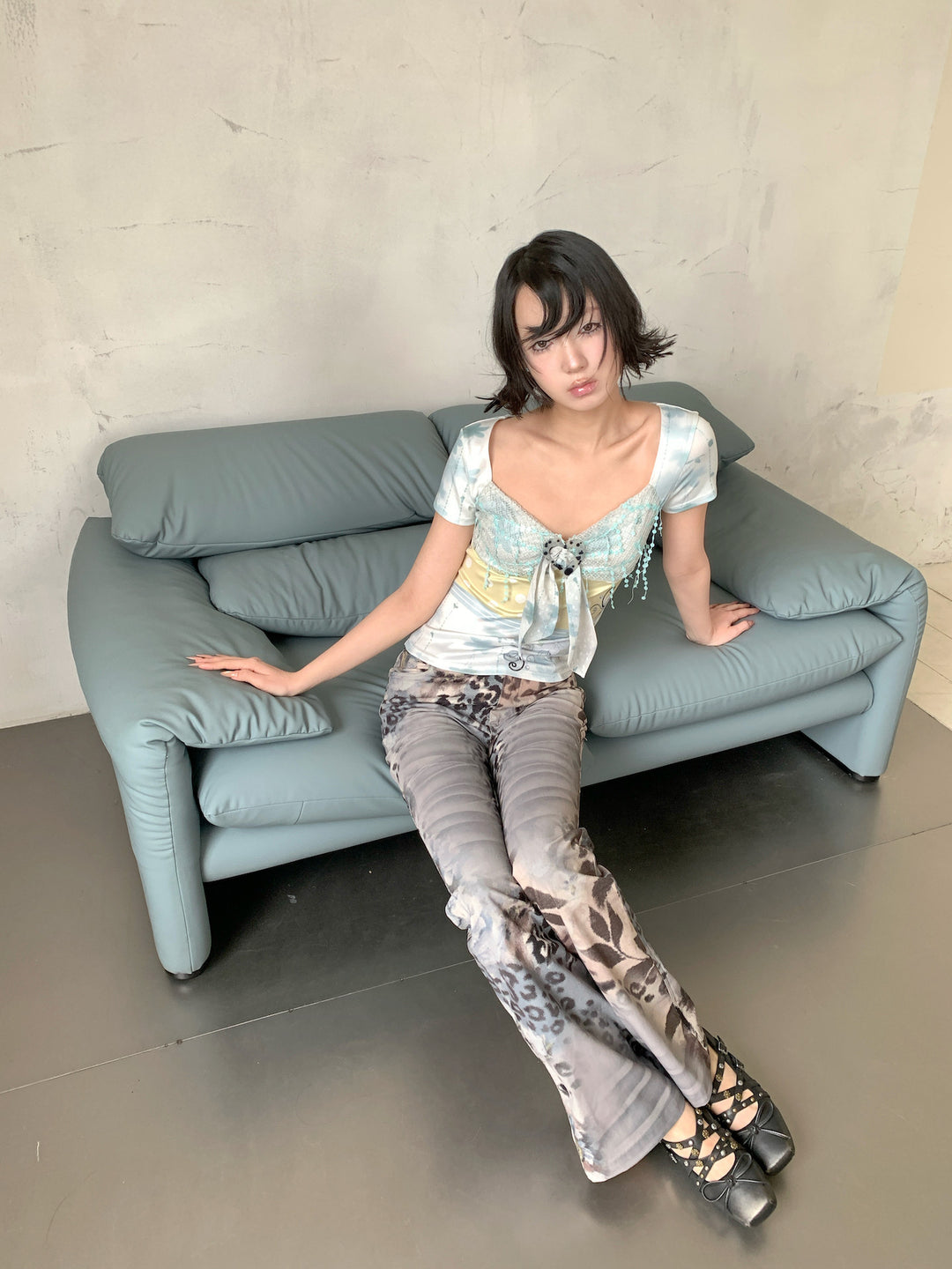 4RE1GN BLUE BLOOM patchwork short-sleeve tee in blue multicolor — modeled view seated on a sofa