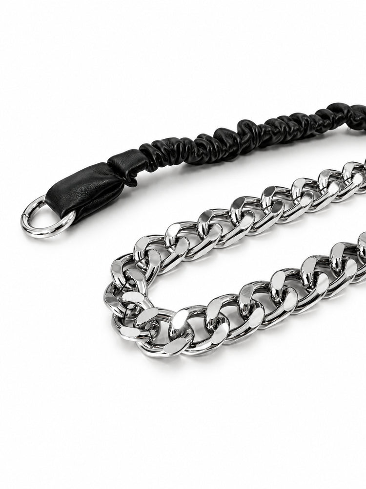 WRAVEN polished silver-tone curb links beside the black gathered faux-leather strap, studio close-up.