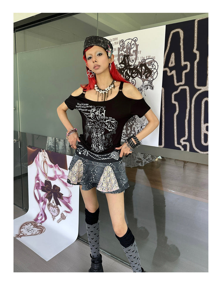 4RE1GN CROSS SCRIPT cold-shoulder tee in black — modeled view beside the display with hands at the waist