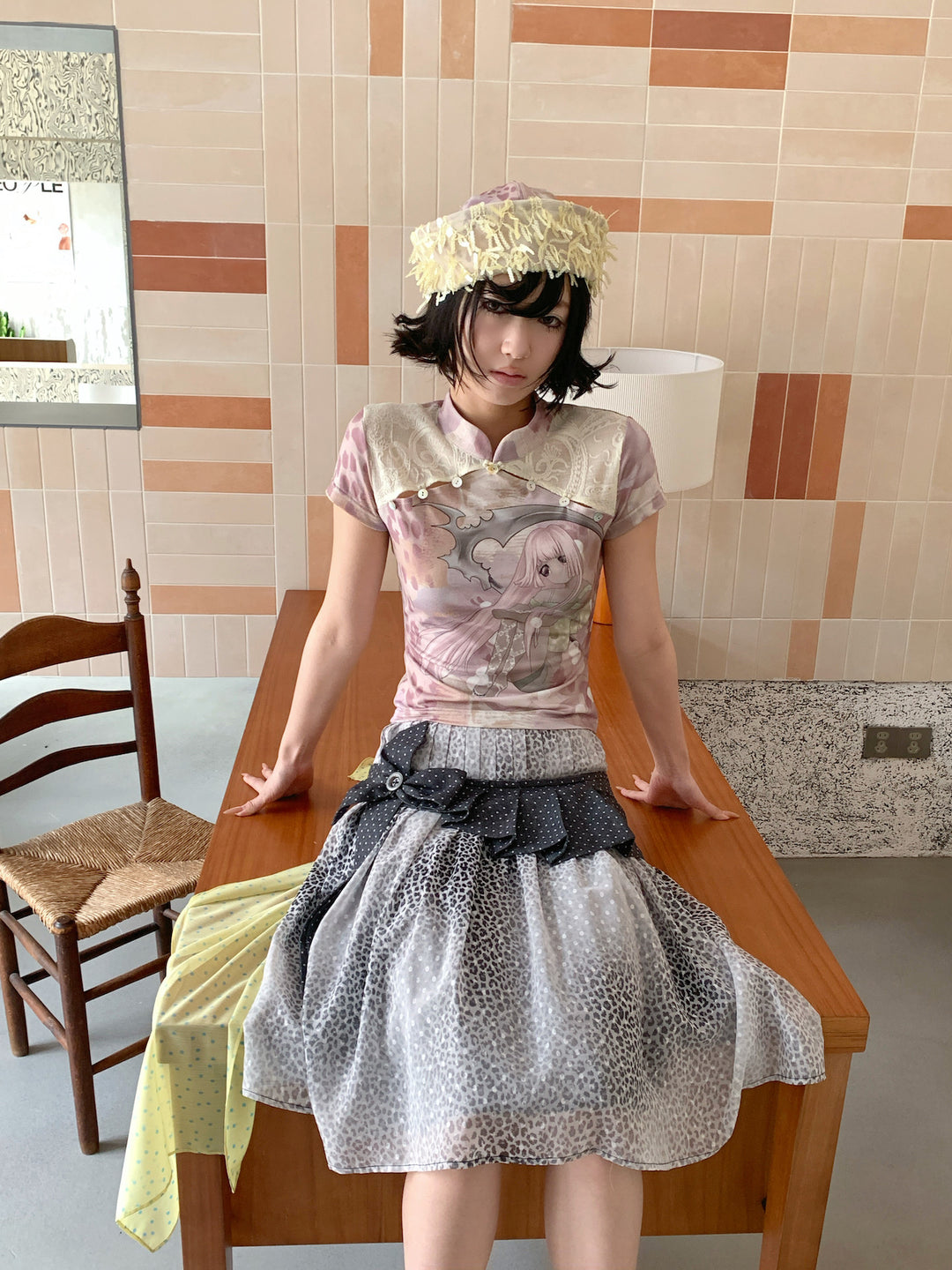 4RE1GN PINK REAPER lace-panel mandarin tee in pink multicolor — front modeled view seated on a wooden cabinet