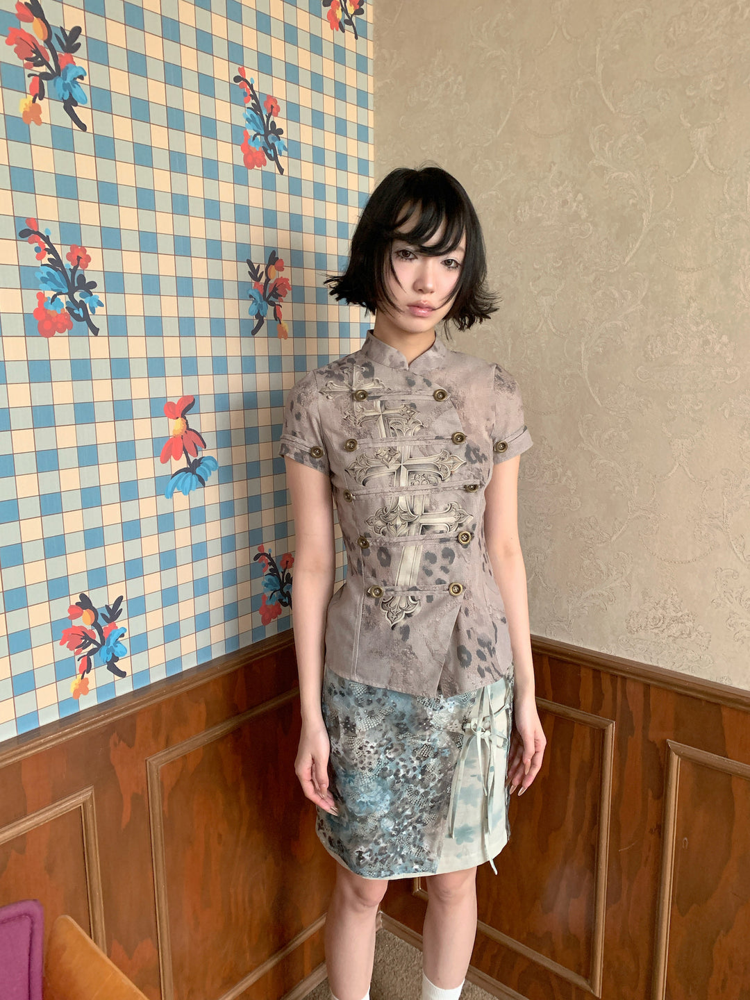 4RE1GN BLUE BLOOM tie-front layered skirt in blue multicolor — front modeled view beside a patterned wall