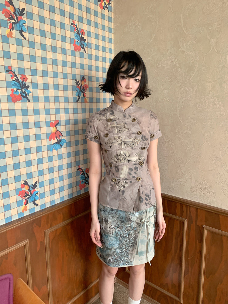 4RE1GN BLUE BLOOM tie-front layered skirt in blue multicolor — front modeled view beside a patterned wall