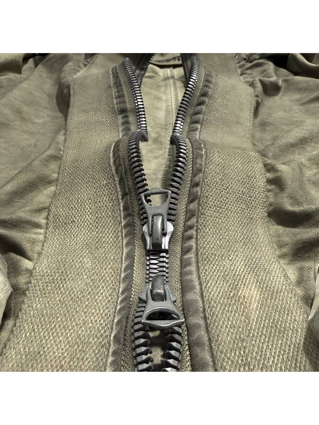 STARCORE distressed work jacket in lunar soil green — close-up of the two-way zipper and woven placket