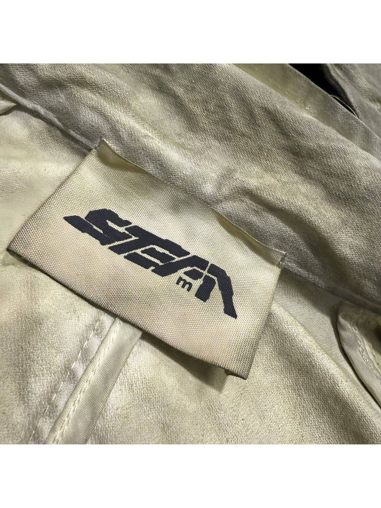 STARCORE distressed work jacket in lunar soil green — close-up of the STEAM brand label and textured fabric