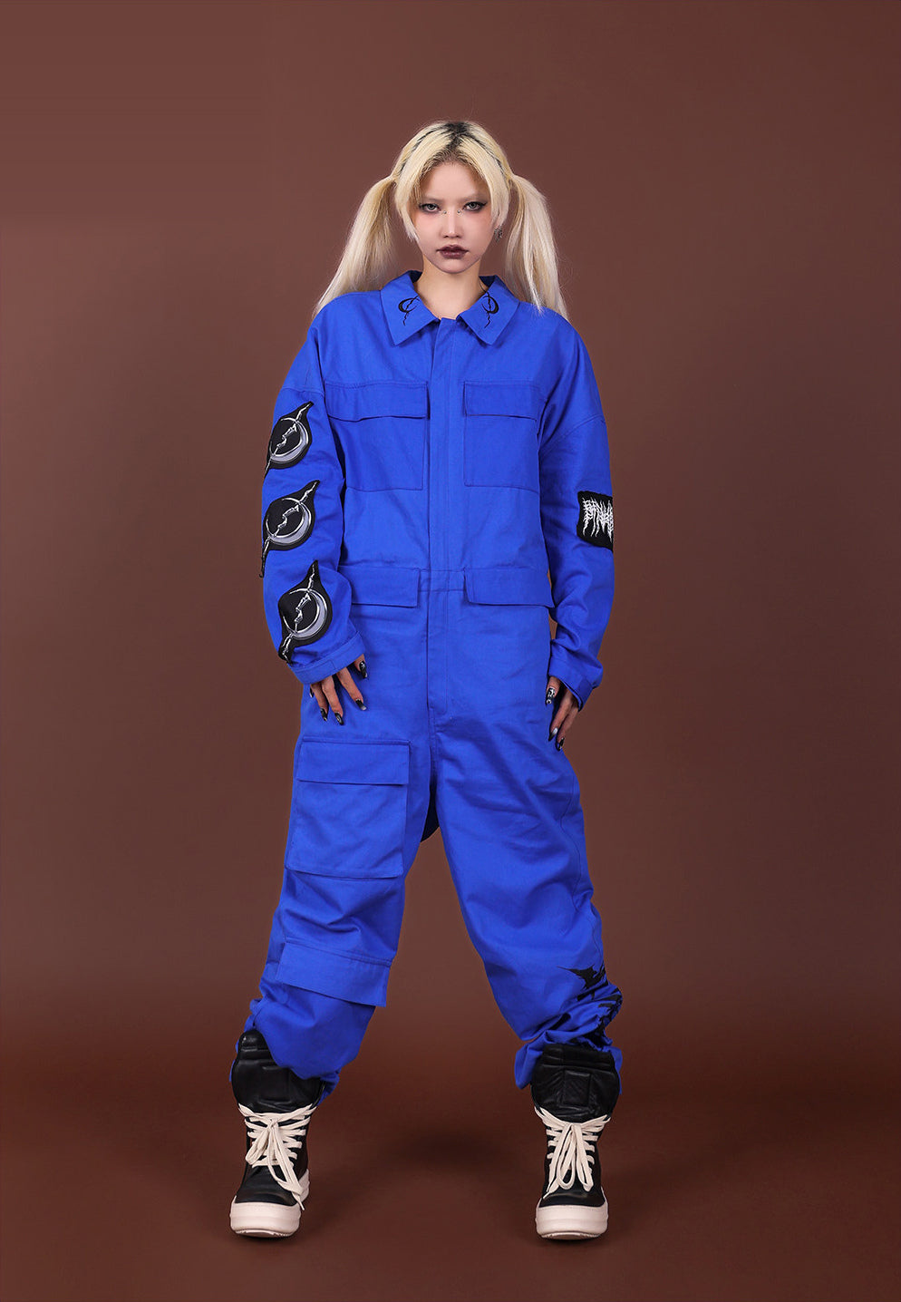 Front view of the blue REMAKE jumpsuit with hands beside the thigh pocket