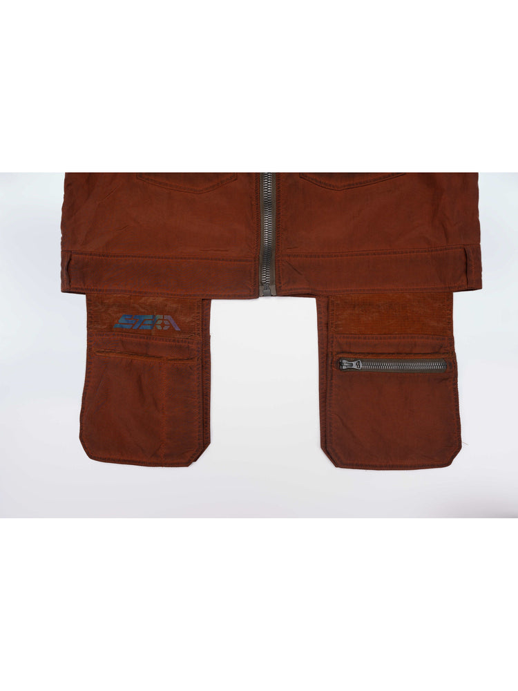 PIONEER sedna-red multi-pocket vest — close-up of the front cargo panels, iridescent logo and zip pocket