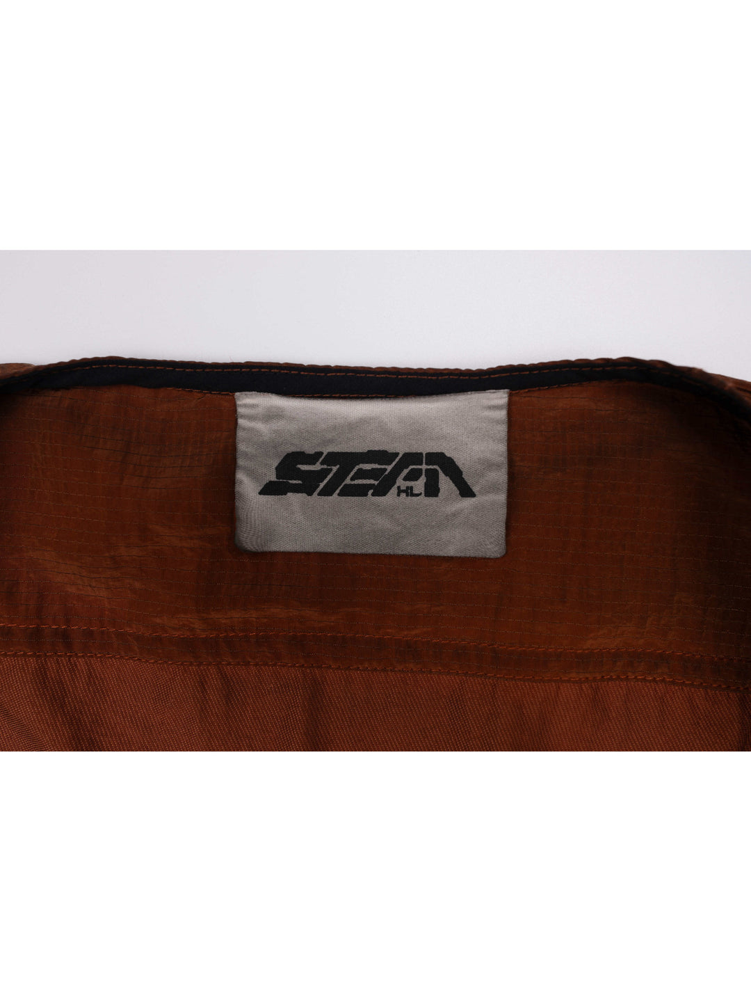 PIONEER sedna-red multi-pocket vest — close-up of the sewn brand label and fabric texture