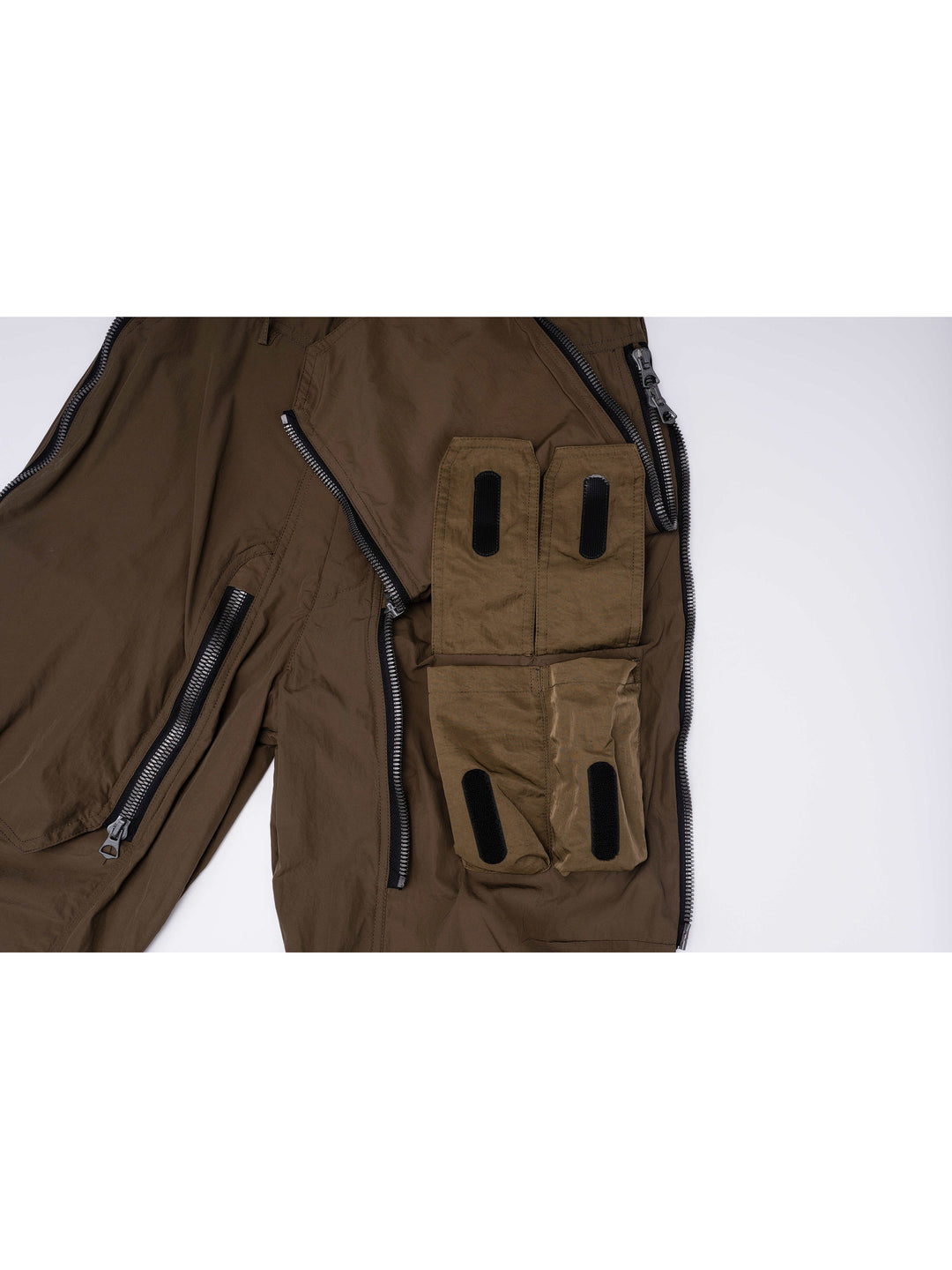 GAIA curved-blade technical pants in stone green — cargo pocket detail showing the layered compartments