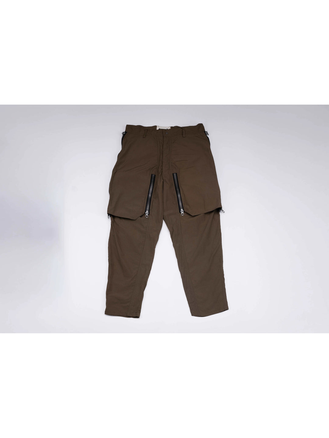 GAIA curved-blade technical pants in stone green — front garment-only view with curved zip panels closed